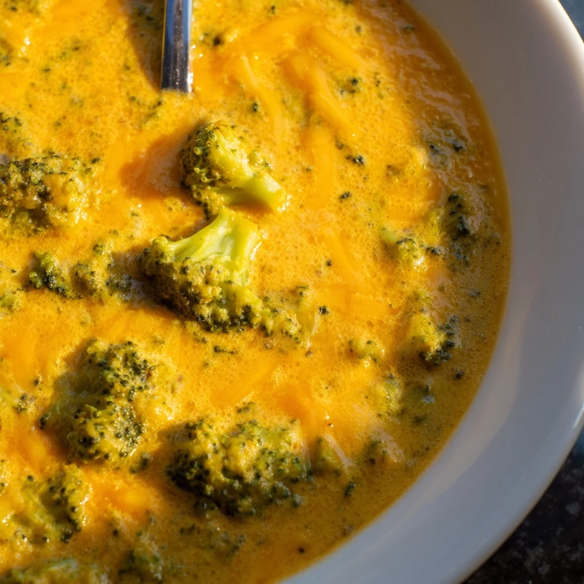 A warm, comforting bowl of Creamy Broccoli Cheddar Soup, blended smooth and served with a side of toasted artisan bread.