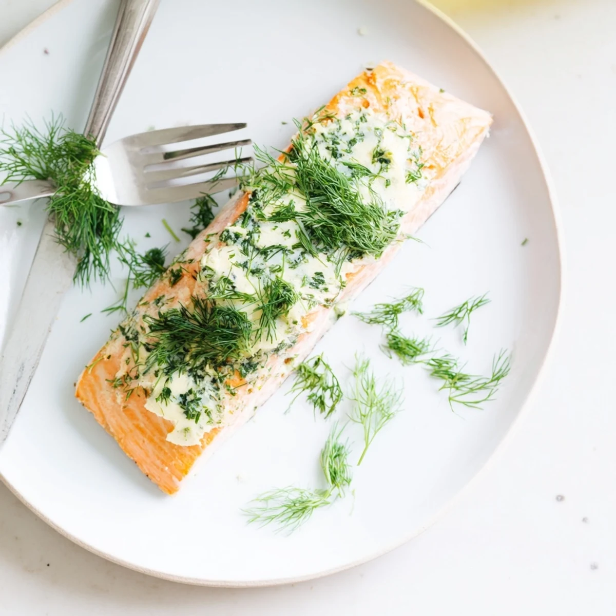 Flaky, oven-baked salmon fillets with a generous dollop of dill butter, garnished with fresh dill sprigs.