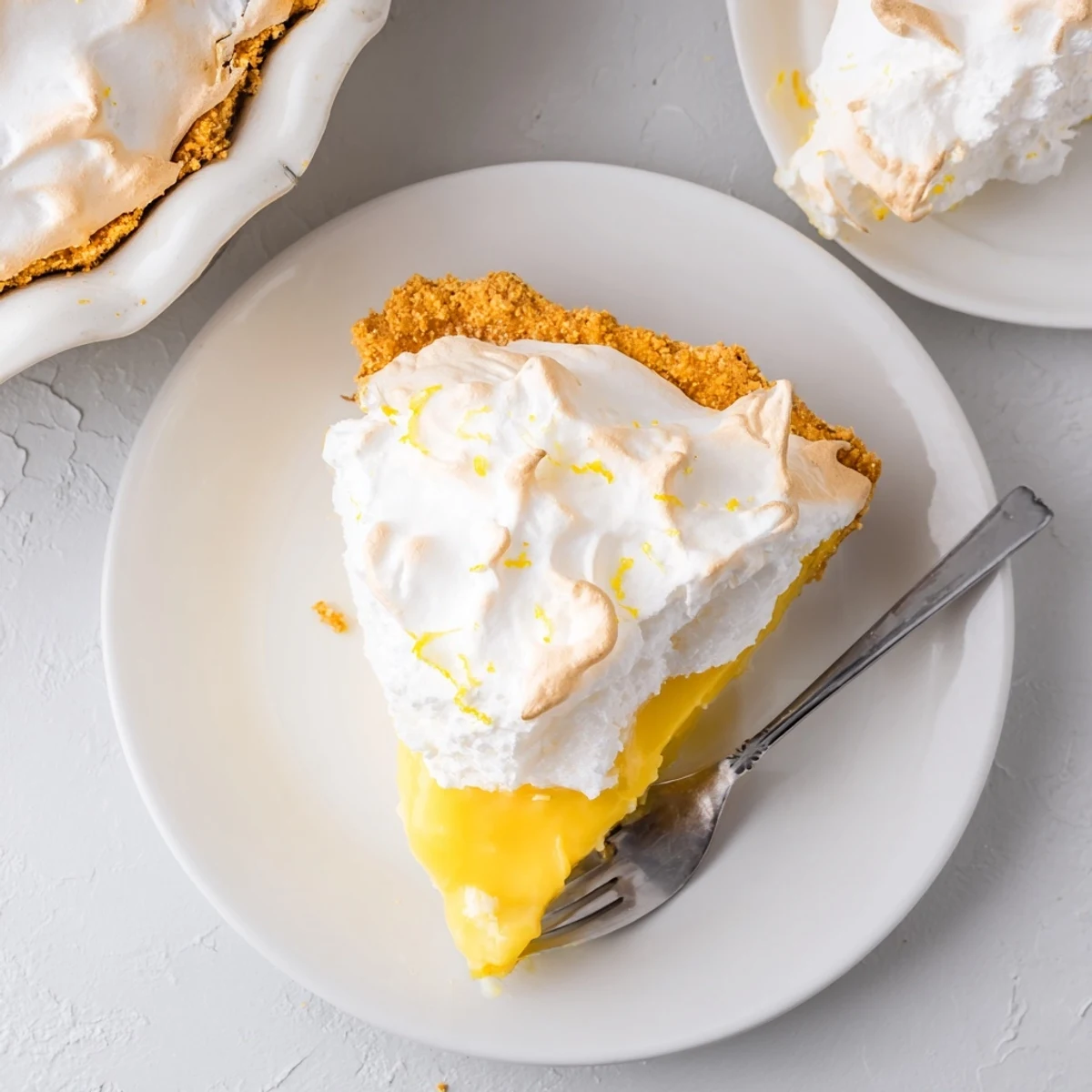 Homemade Lemon Meringue Pie with a crumbly graham cracker crust, ready to serve with tea.