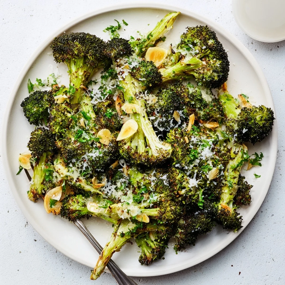 Roasted Broccoli with Garlic and Parmesan features golden, tender-crisp florets with melted cheese on a serving plate.