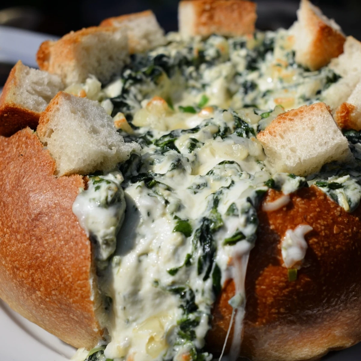 A rich, golden-brown Creamy Spinach Dip baked in a hollowed sourdough loaf, perfect for a cozy gathering.