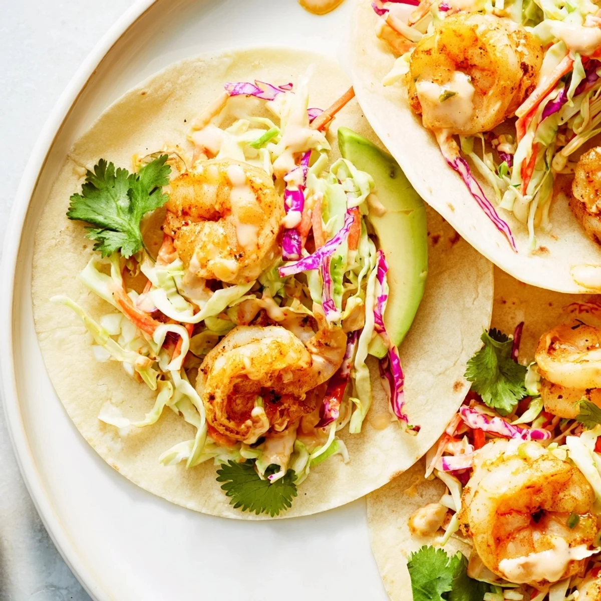 Fresh avocado slices top these Cajun Shrimp Tacos with Slaw for a creamy bite.