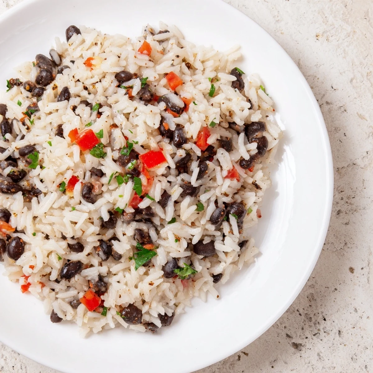 A vibrant bowl of Rice and Beans with Spices, featuring fluffy grains, creamy black beans, and sautéed onions and red bell peppers topped with fresh cilantro.