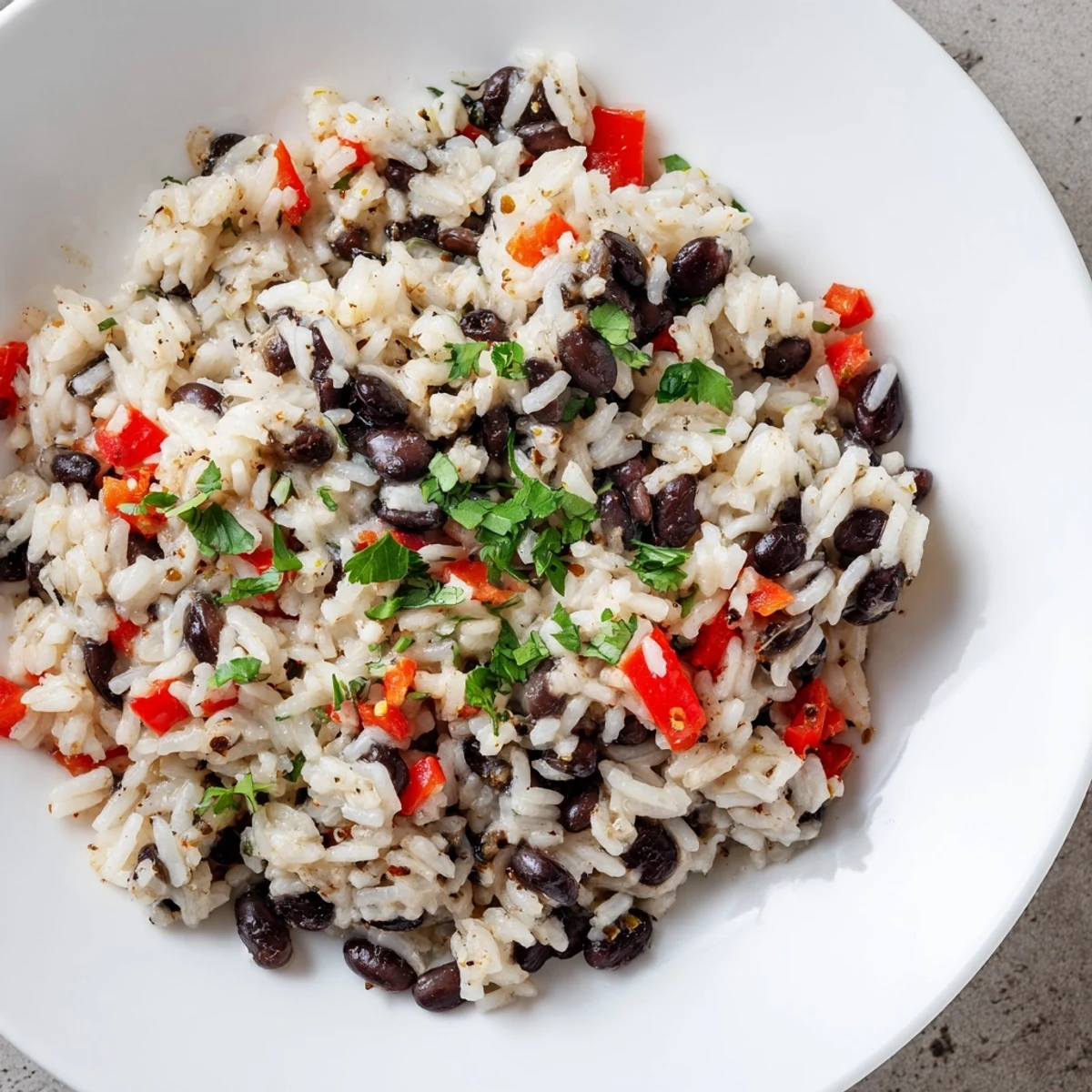 A close-up of Rice and Beans with Spices garnished with lime wedges, fresh cilantro, and diced red bell pepper, perfect for a quick weeknight dinner.