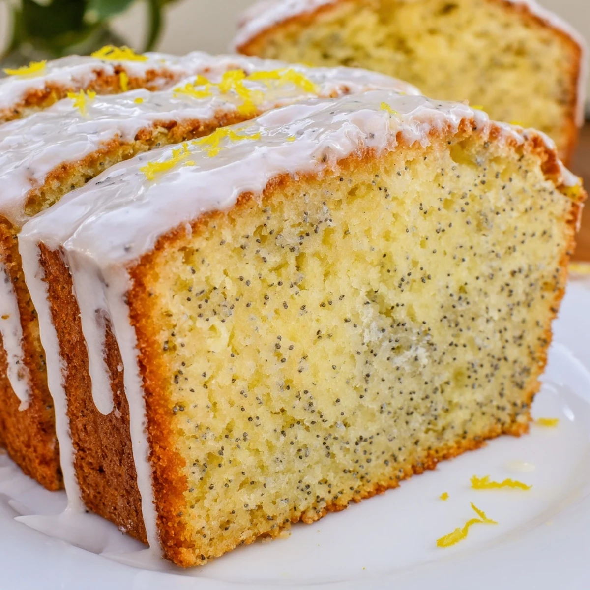 A close-up slice of Lemon Poppy Seed Loaf showing a moist crumb with visible poppy seeds.
