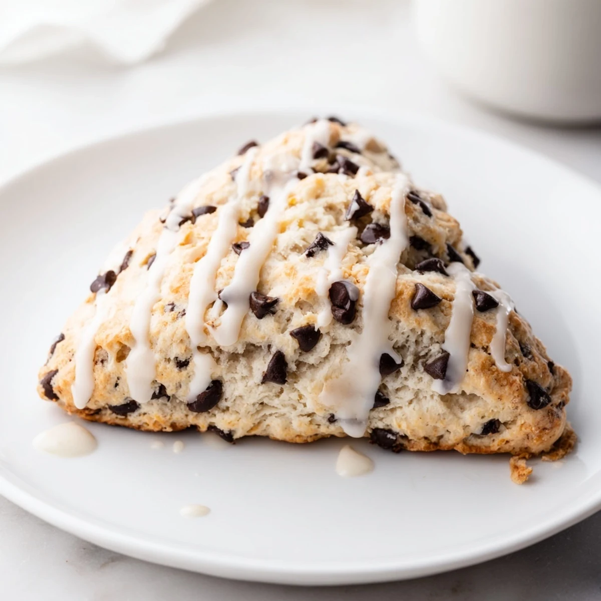 Warm Chocolate Chip Scones with Vanilla Glaze drizzled over stacked scones on a marble countertop.