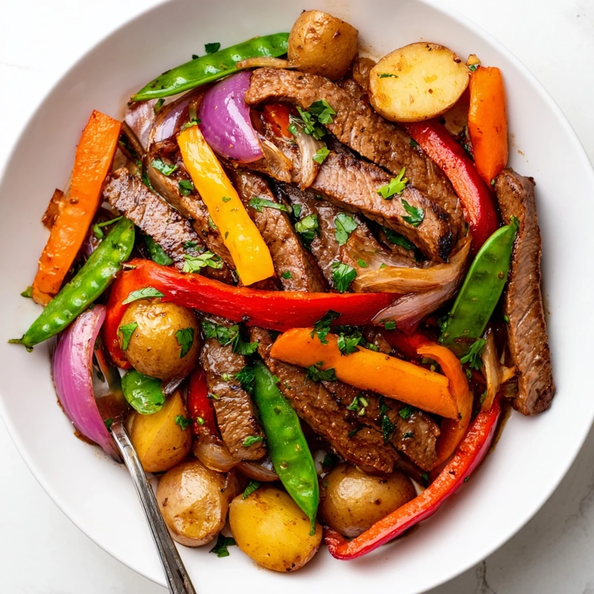 Close-up of Blackstone Cowboy Stir Fry Dinner featuring caramelized beef, crisp snap peas, and golden potatoes, drenched in a glossy, savory sauce.
