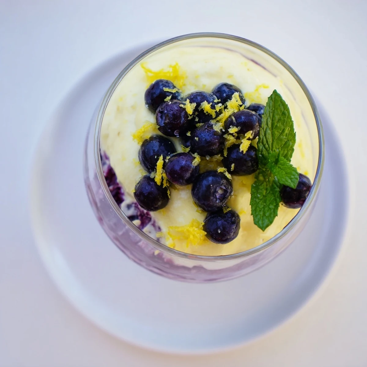 A spoon dips into the creamy Lemon Blueberry Mousse above a blueberry compote layer. 
