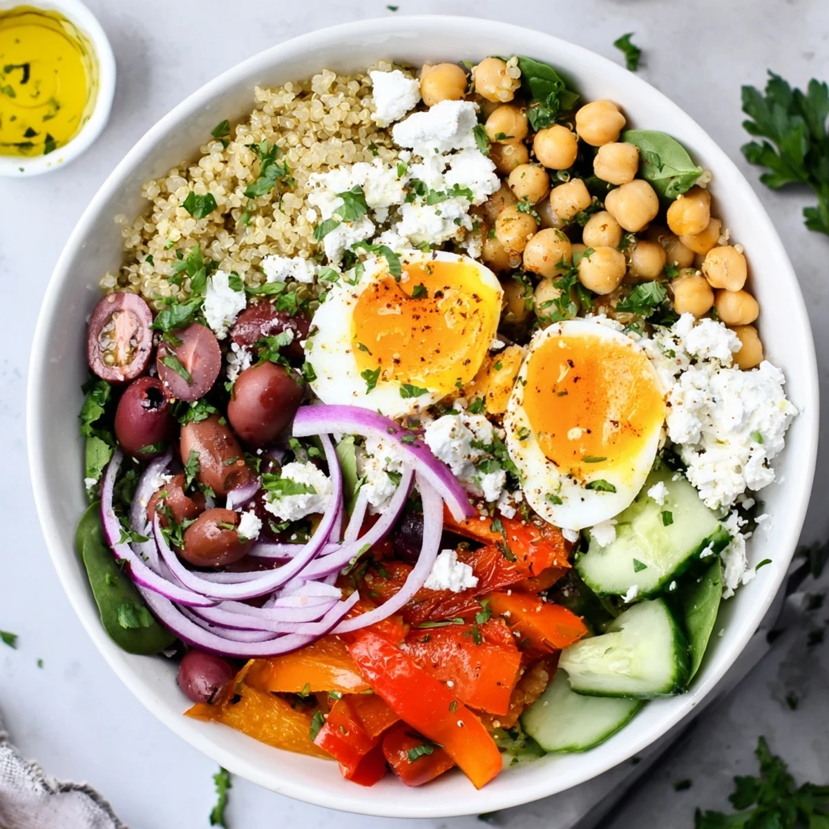 A close-up of the High Protein Mediterranean Breakfast Bowls highlights a swirl of Greek yogurt, chopped parsley, and glistening olive oil drizzled over roasted red peppers and chickpeas.