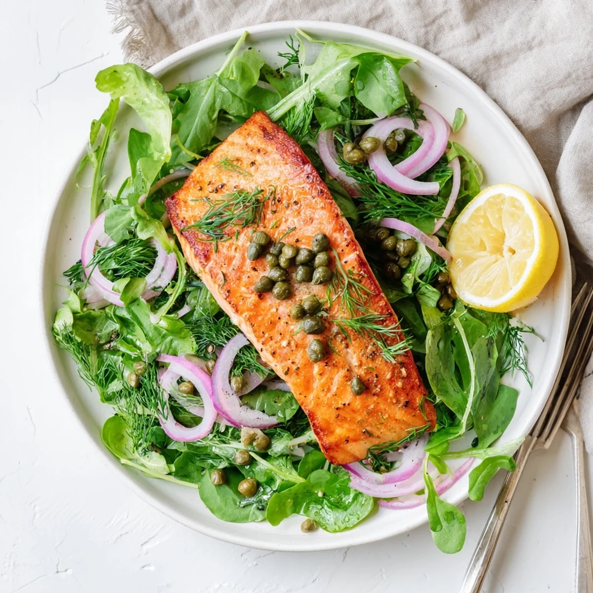 Chef plating Tasmanian Atlantic salmon showcasing crispy skin atop a vibrant herb salad with capers and lemon zest.