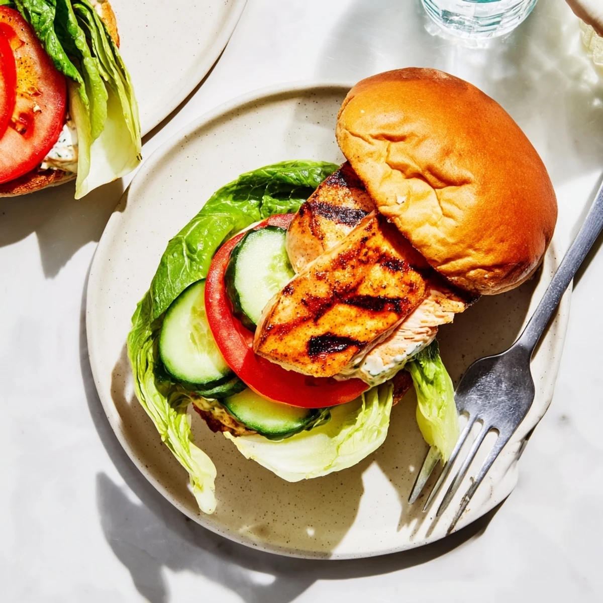 A close-up of the BBQ Barramundi Burger with charred greens and a zesty lemon jalapeño tartare on top.