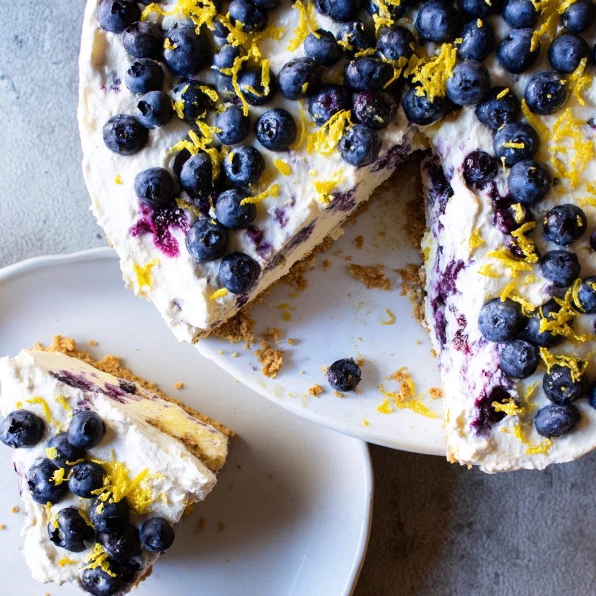 Creamy no bake lemon blueberry cream cake topped with fresh berries on a graham cracker crust