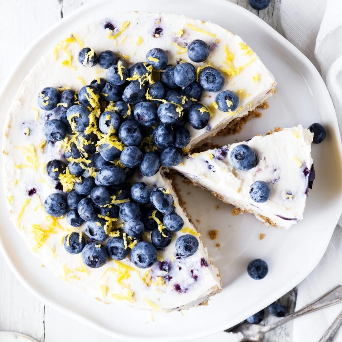 Slice of refreshing no bake lemon blueberry cream cake with vibrant blueberries and lemon zest garnish