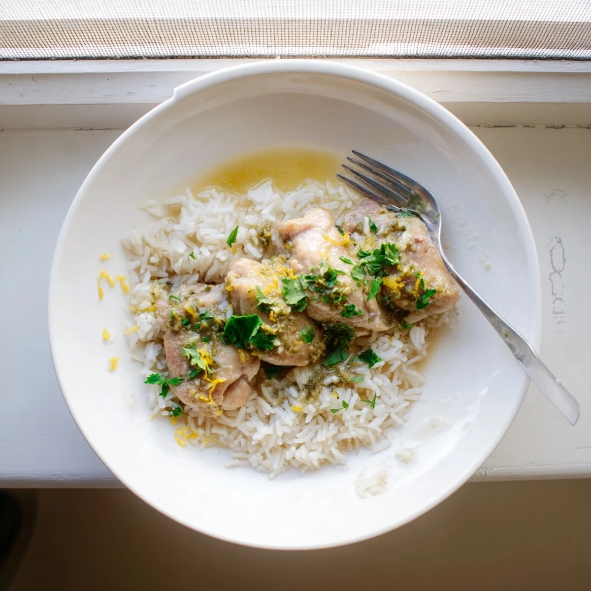 Juicy lemon herb chicken drizzled with cooking juices over perfectly cooked fluffy white rice