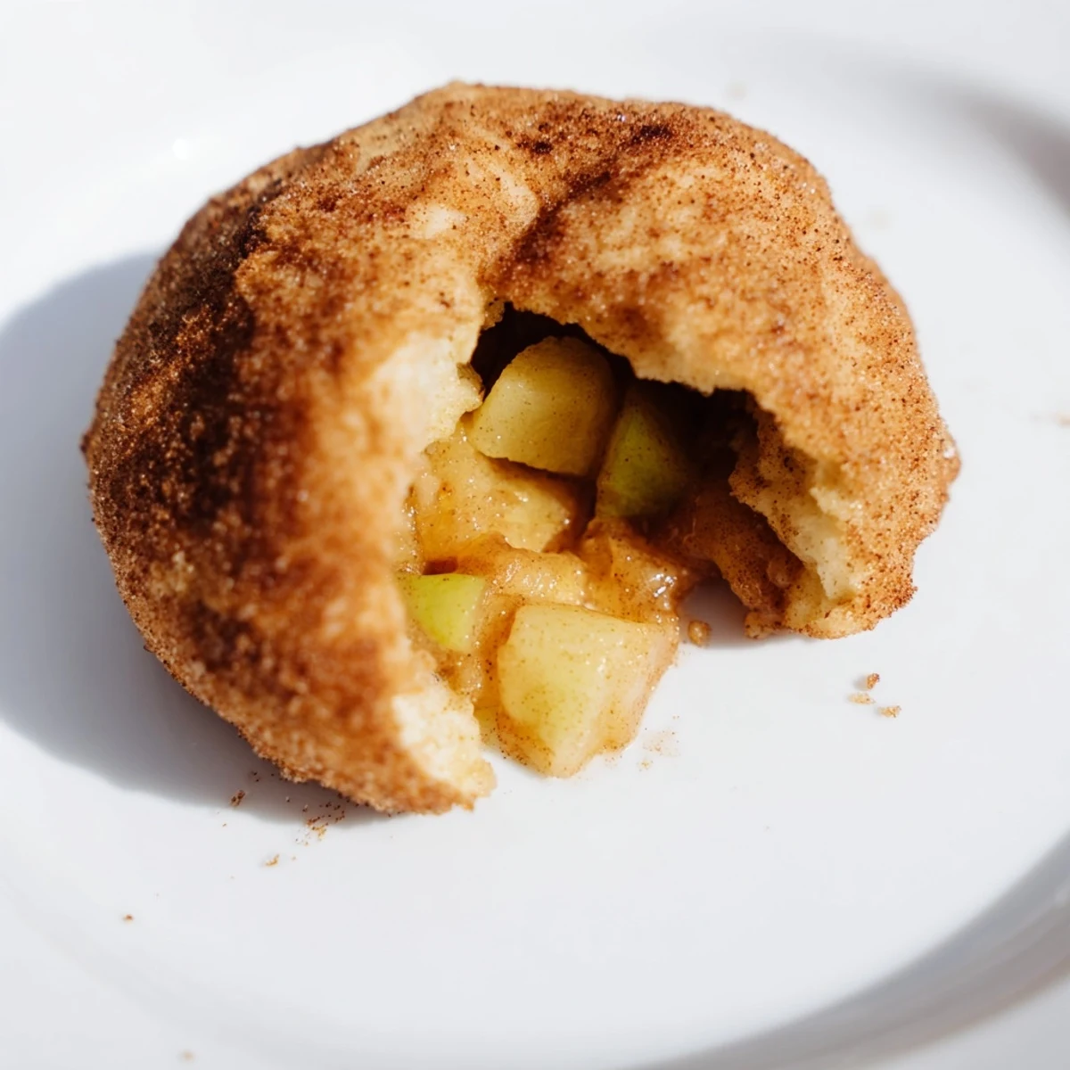 Golden brown caramel apple pie bombs with cinnamon sugar coating on a parchment-lined baking sheet