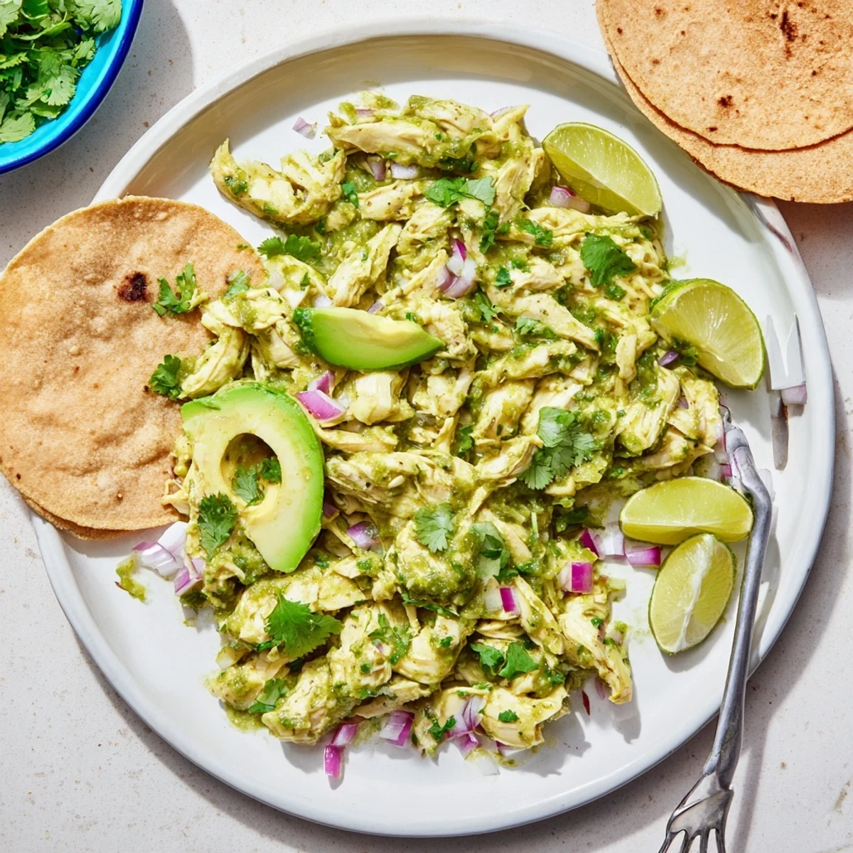 Golden chicken pieces bubbling in vibrant green salsa verde sauce, topped with diced red onion