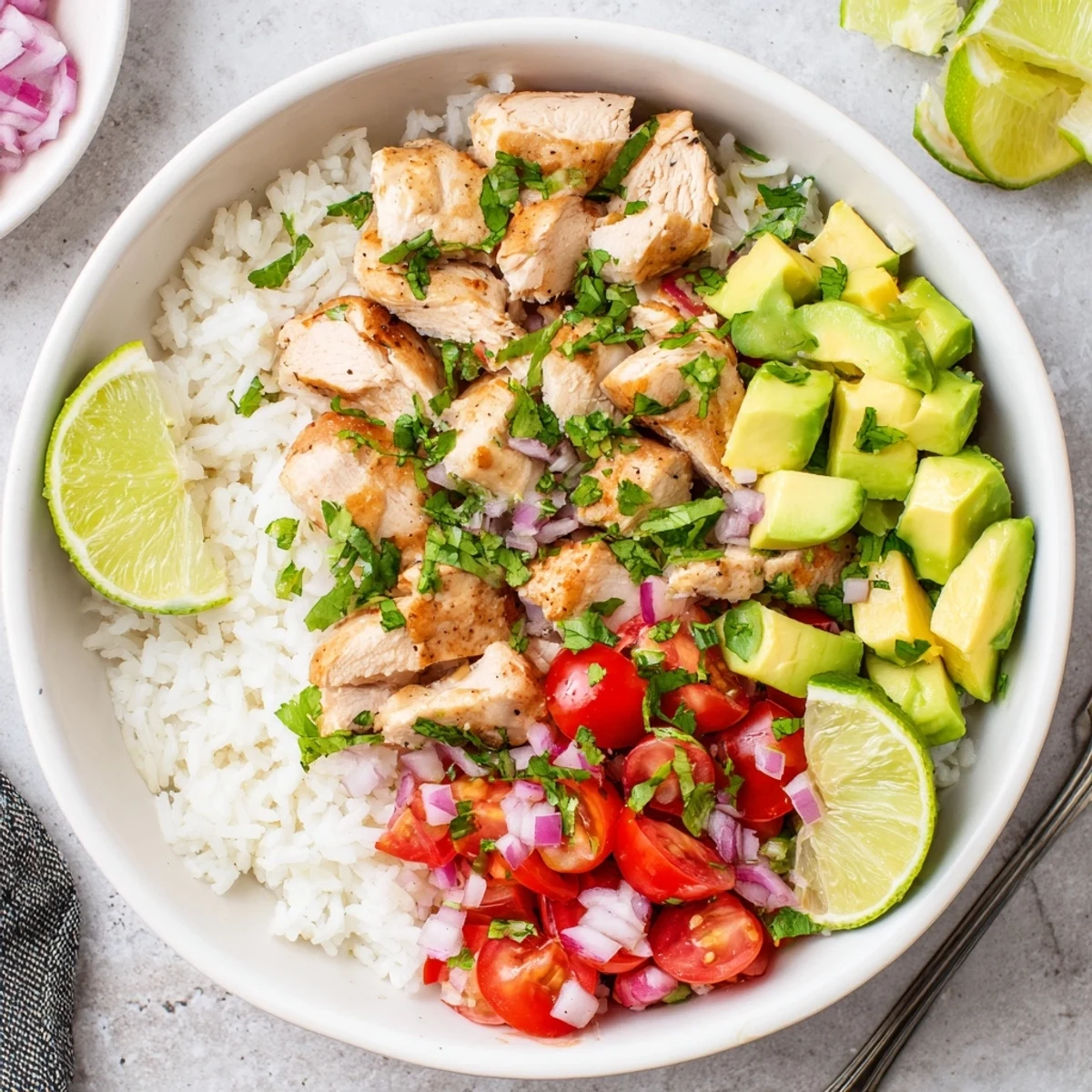 Vibrant rice bowl featuring tender marinated chicken breast with ripe avocado chunks cherry tomatoes and red onion