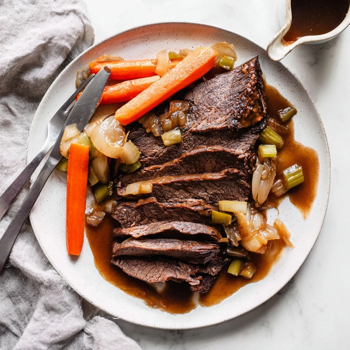 Fork-tender slow cooker beef brisket plated with roasted carrots and savory tangy glaze