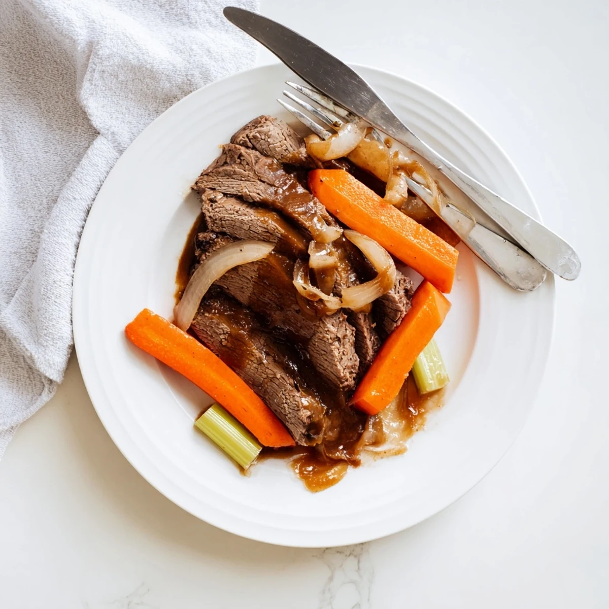 Succulent slow cooker beef brisket resting on a platter with onions and ladled gravy