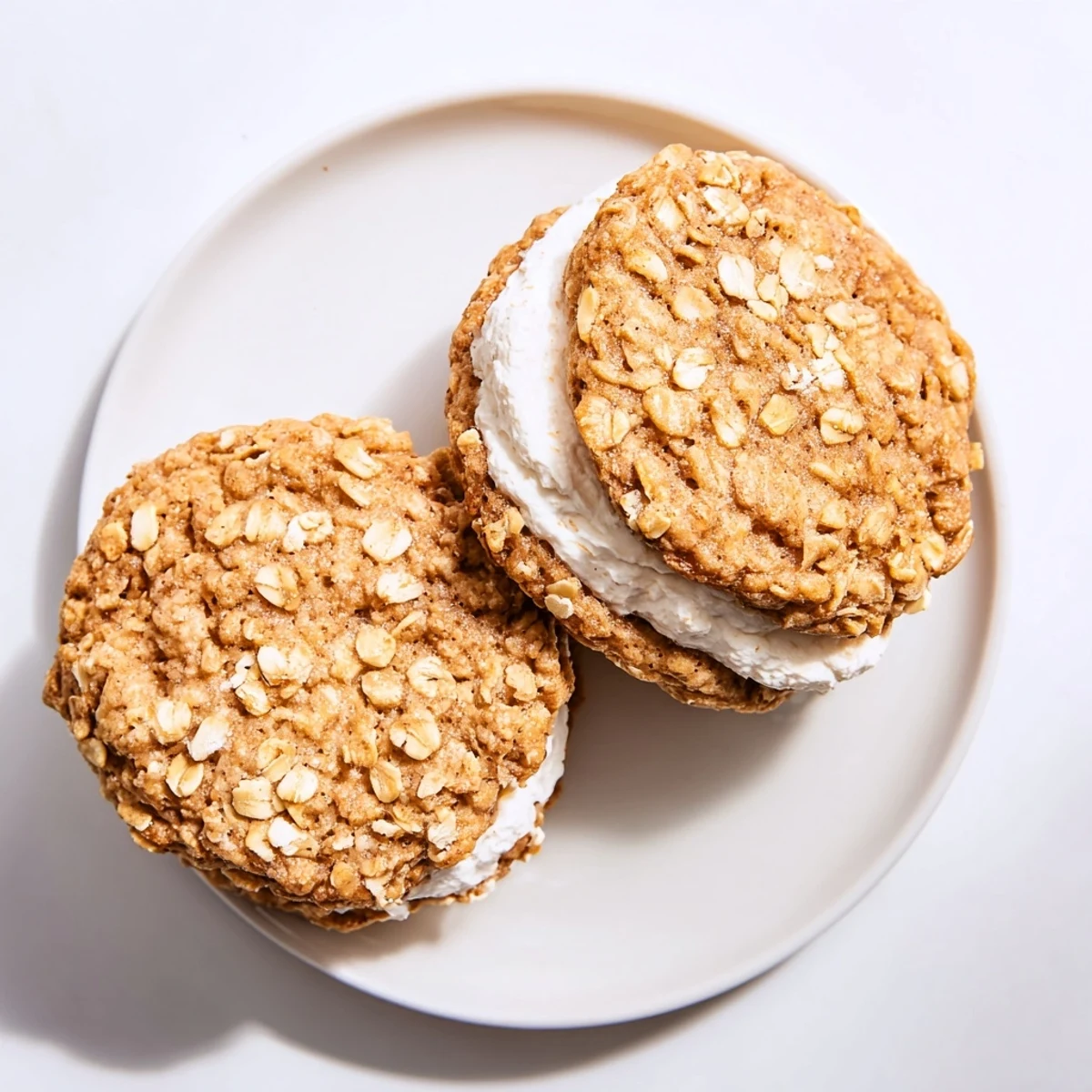 Soft chewy oatmeal cookies stacked with sweet cream filling revealing the textured cookie layers