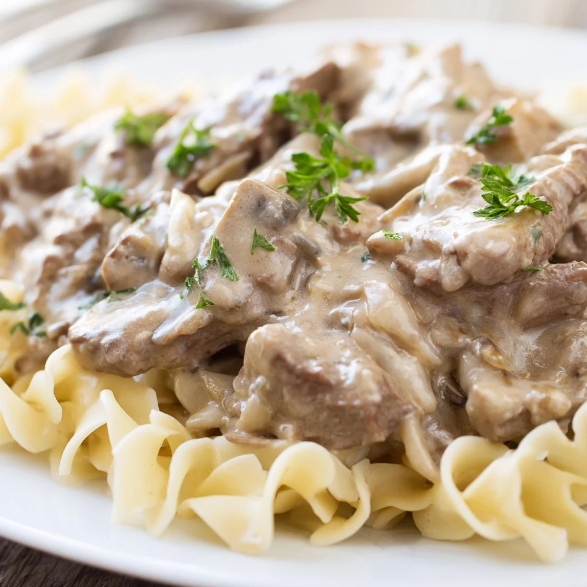 Golden beef stroganoff with creamy mushroom sauce over a bed of egg noodles