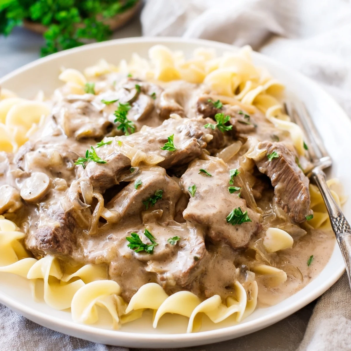 Tender beef strips in rich sour cream sauce with mushrooms, garnished with fresh parsley