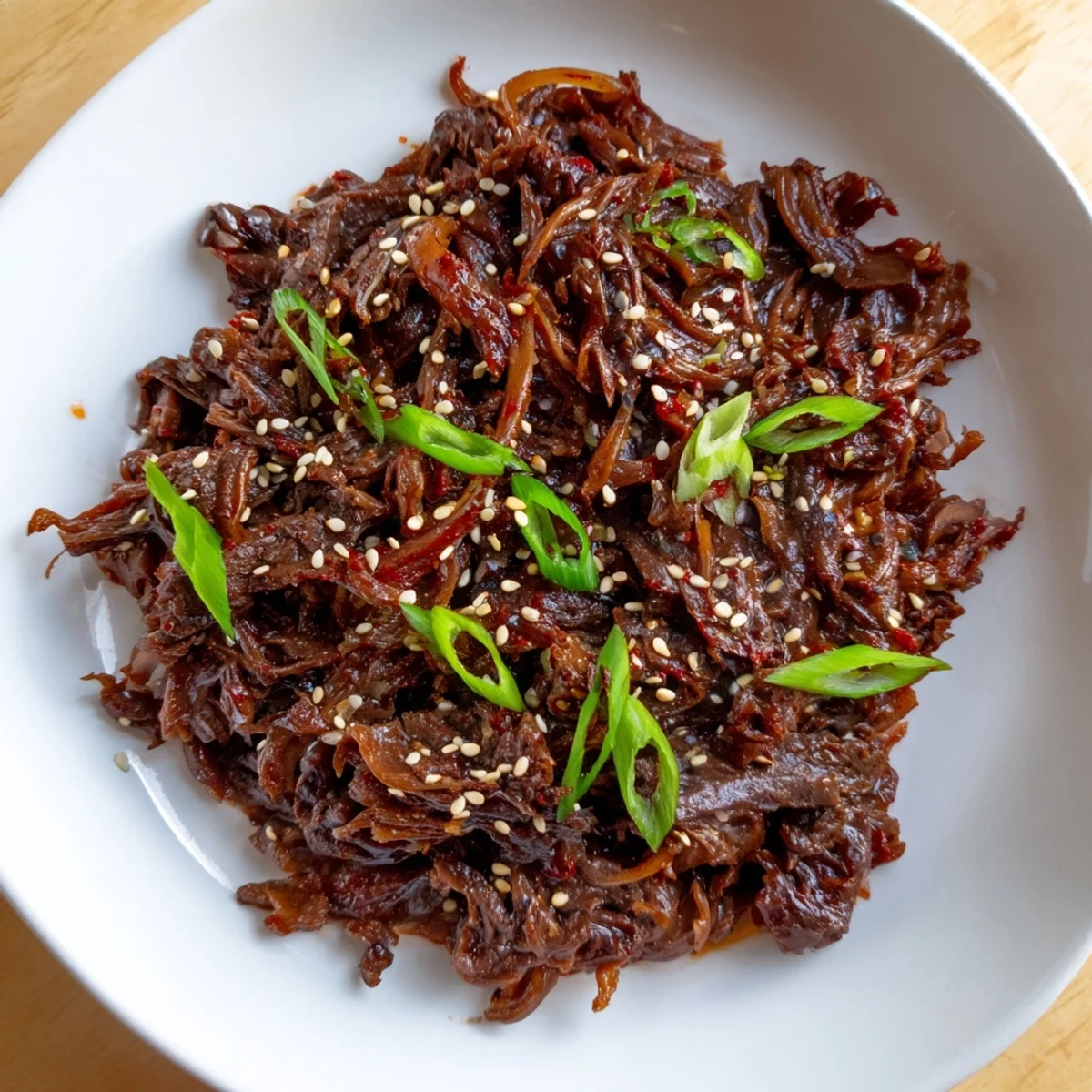 Slow cooker Korean beef recipe featuring caramelized sauce and tender meat pieces with sliced onion garnish