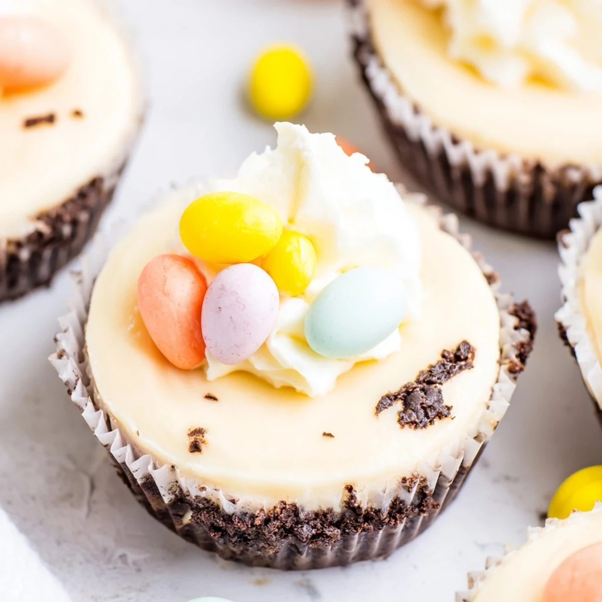 Creamy Easter Cadbury Mini Cheesecakes topped with colorful whipped cream and pastel candy eggs in a muffin tin