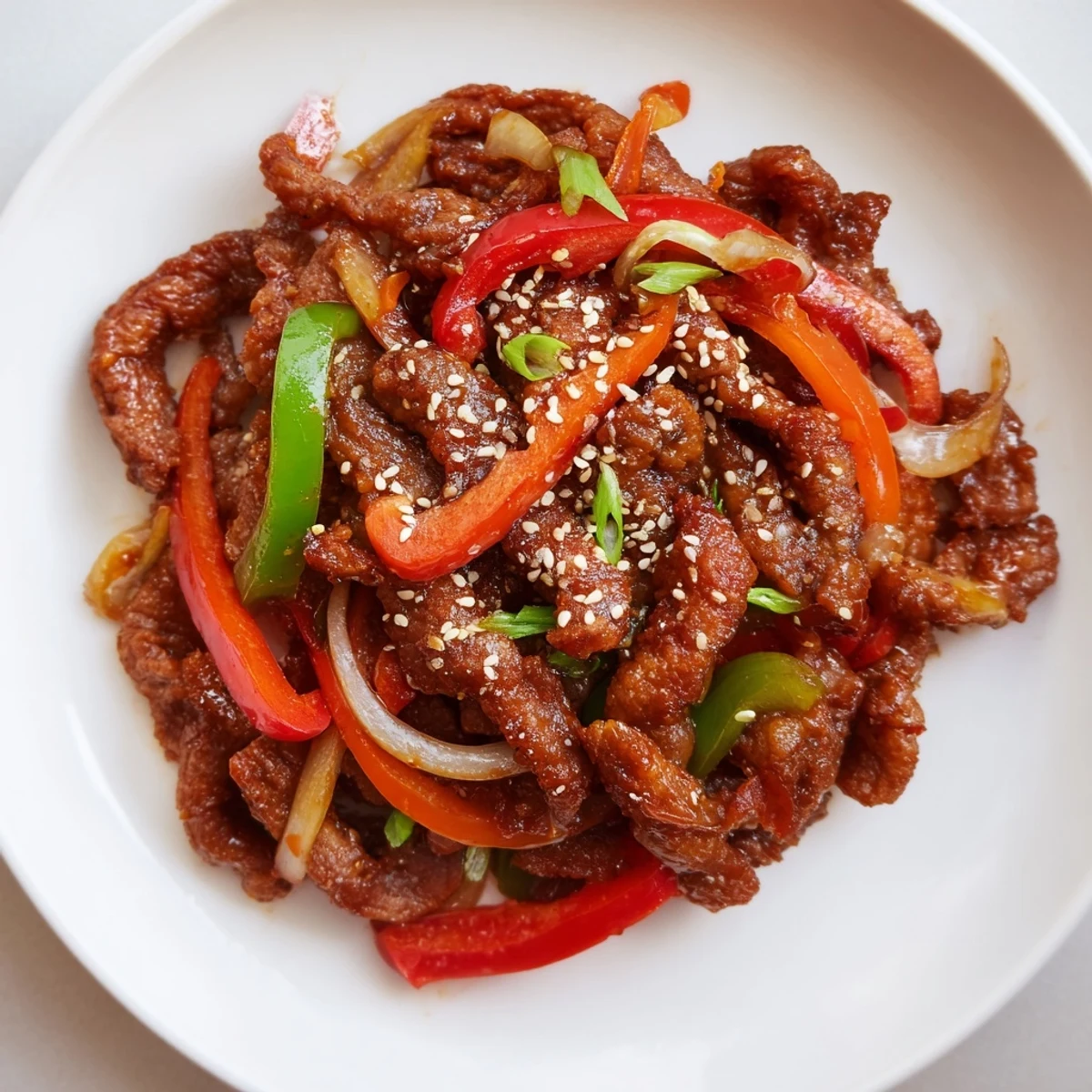 Homemade crispy chilli beef served in a bowl with sesame seeds and fresh green onions