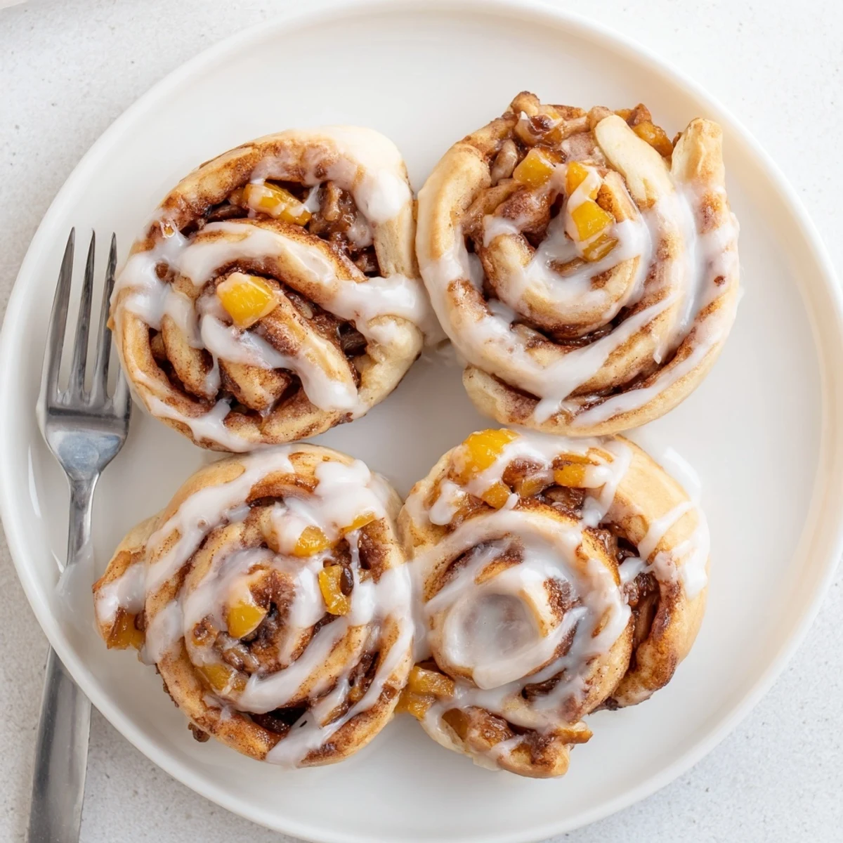 Warm peach pie cinnamon rolls swirled with cinnamon sugar and sweet peach pieces