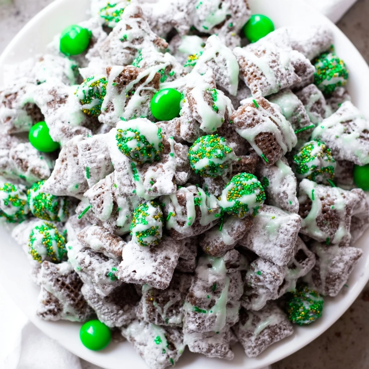 Festive St. Patricks Day puppy chow coated in chocolate peanut butter and decorated with vibrant green sprinkles