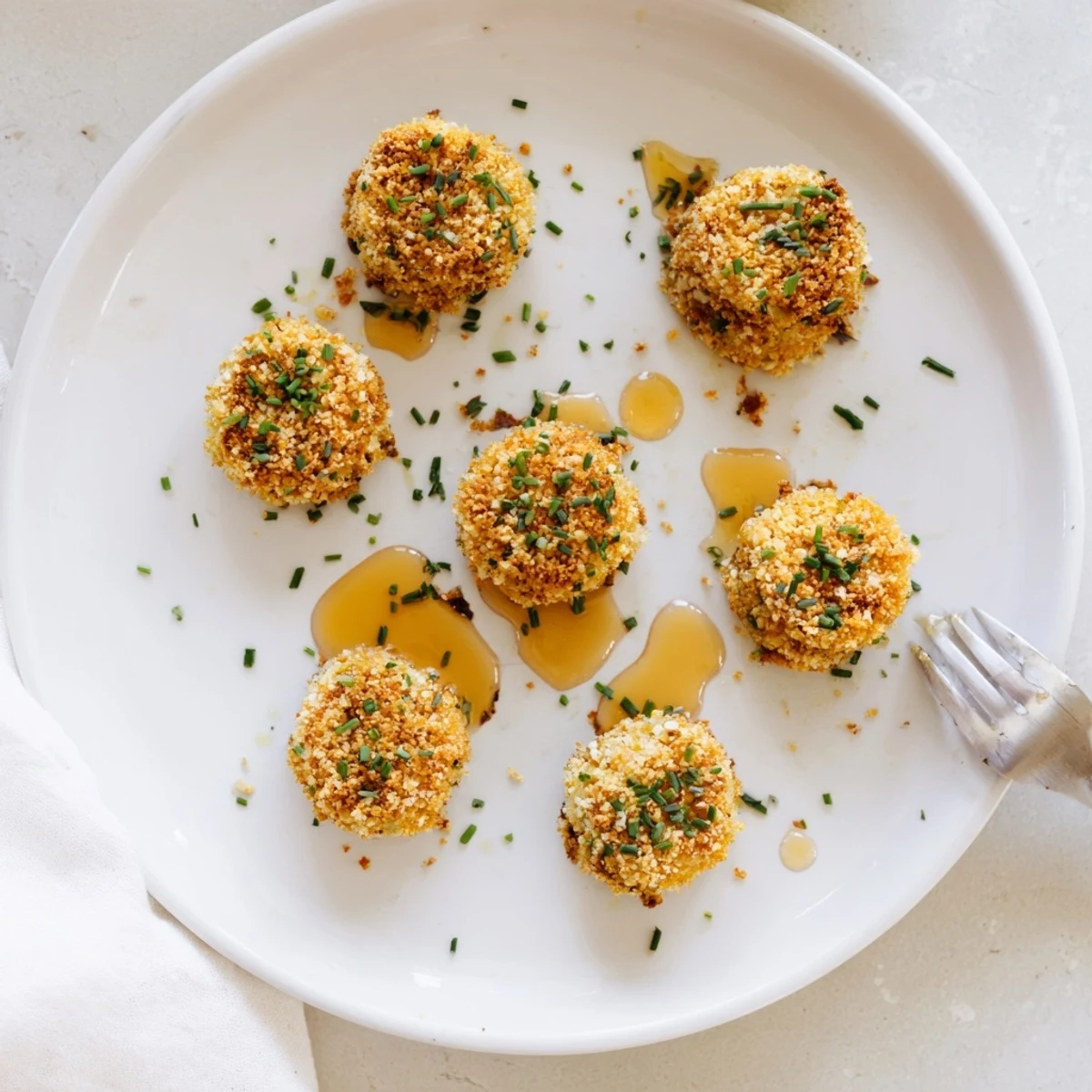 Crispy pretzel crusted goat cheese rounds served warm with balsamic glaze and herbs
