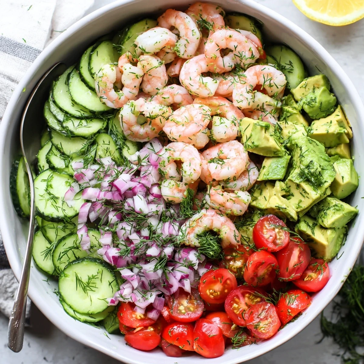 Fresh cucumber shrimp salad featuring tender pink shrimp, crisp vegetables, and zesty lemon dressing in a white bowl