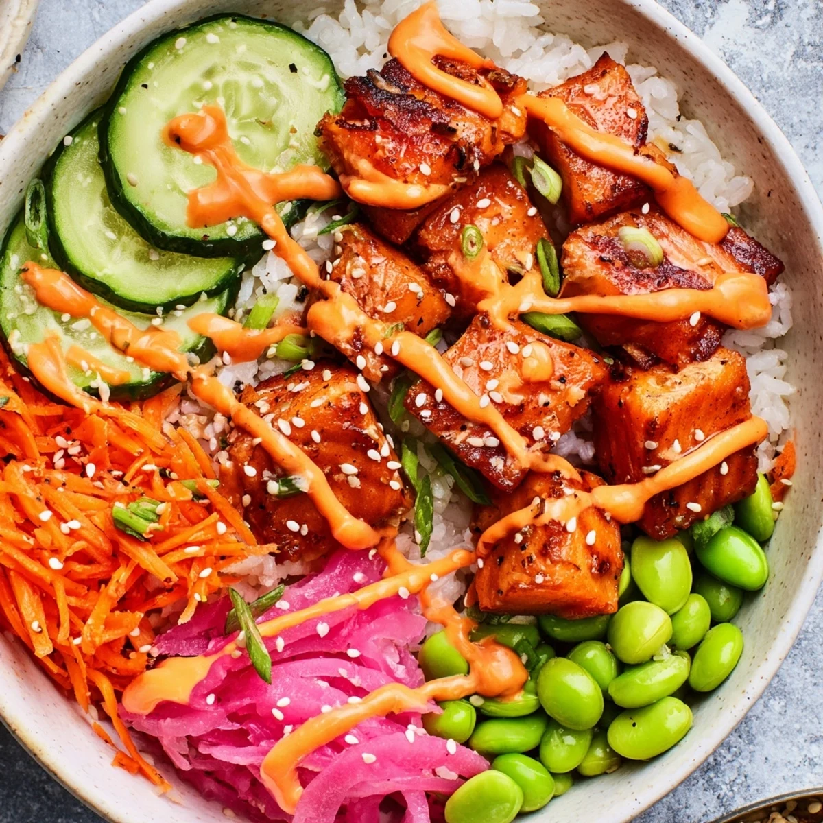 Flaky baked salmon bowl with colorful vegetables and spicy mayo drizzle over rice