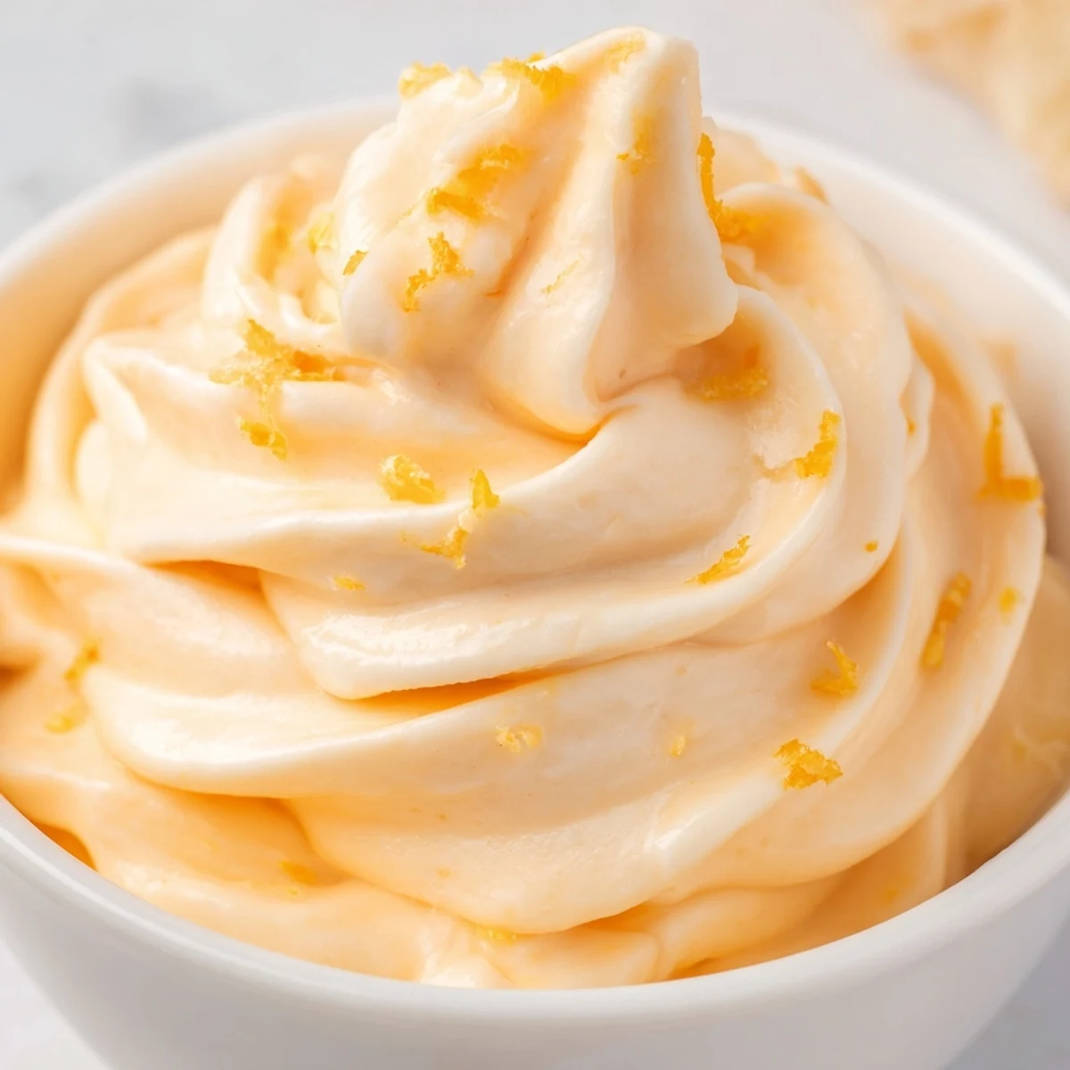 Refreshing frozen homemade orange Dole Whip served in a bowl with pineapple chunks and a spoon