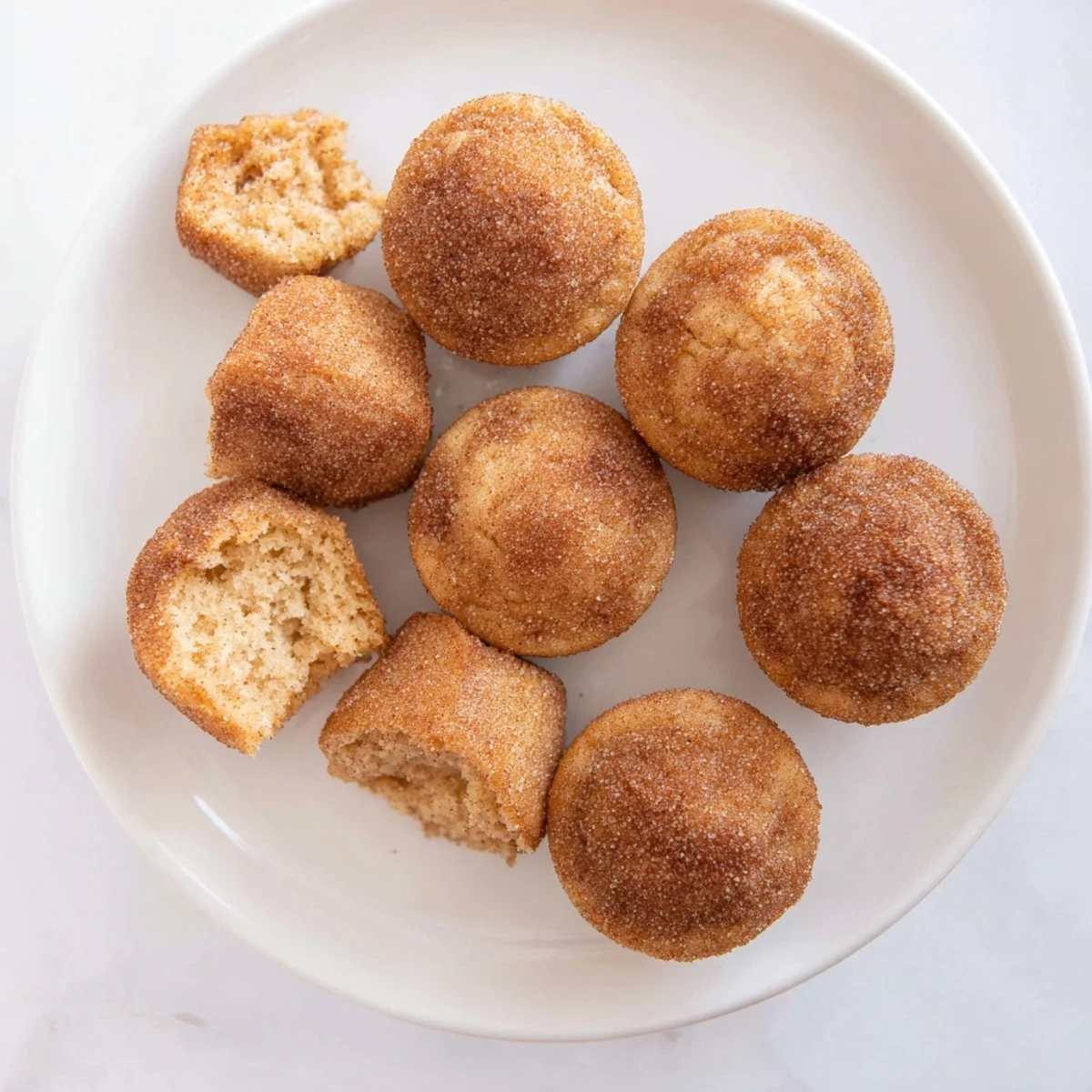 Bite-sized easy cinnamon sugar mini muffins topped with buttery cinnamon sugar on a white plate