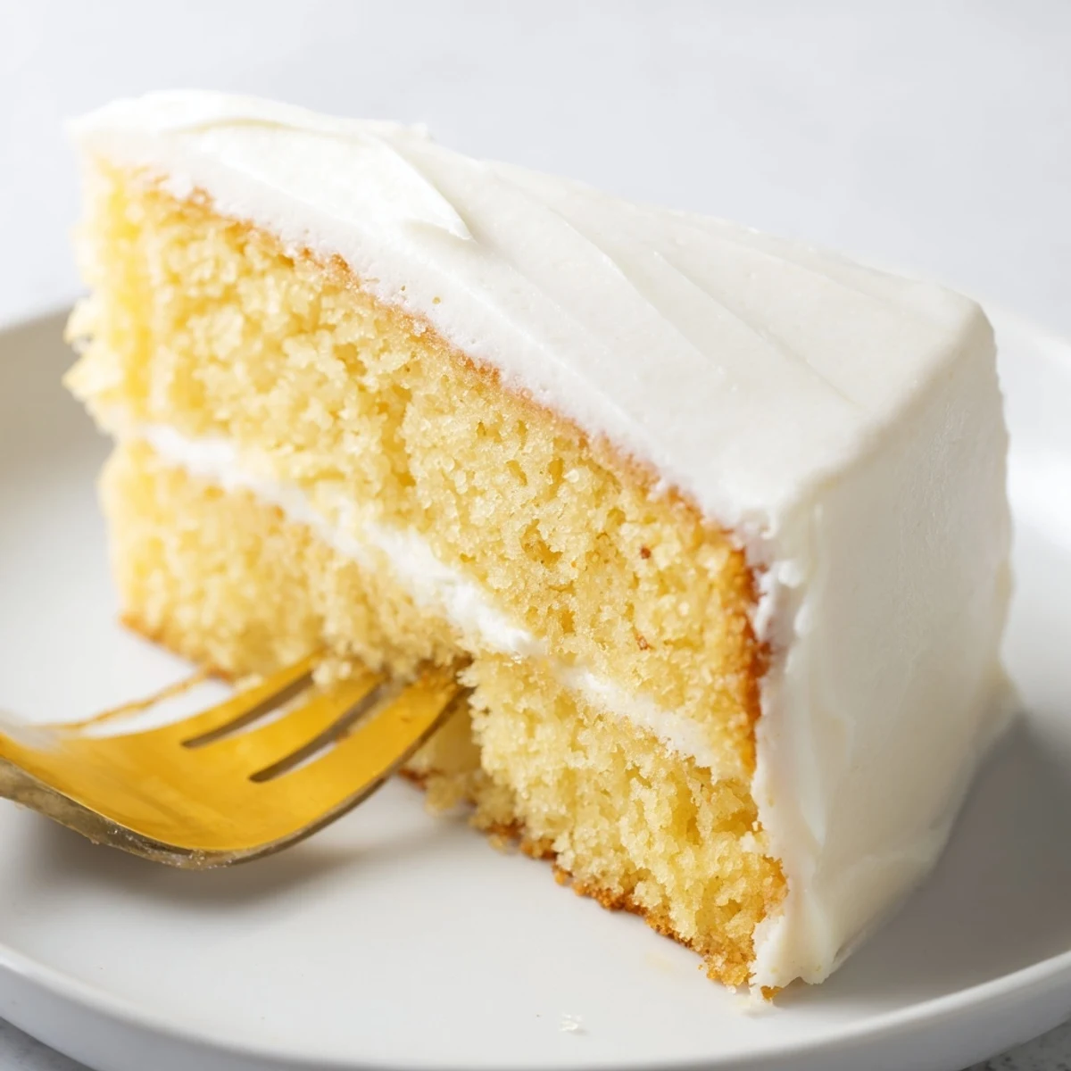Fluffy vanilla church cake with smooth white frosting atop a golden crumb