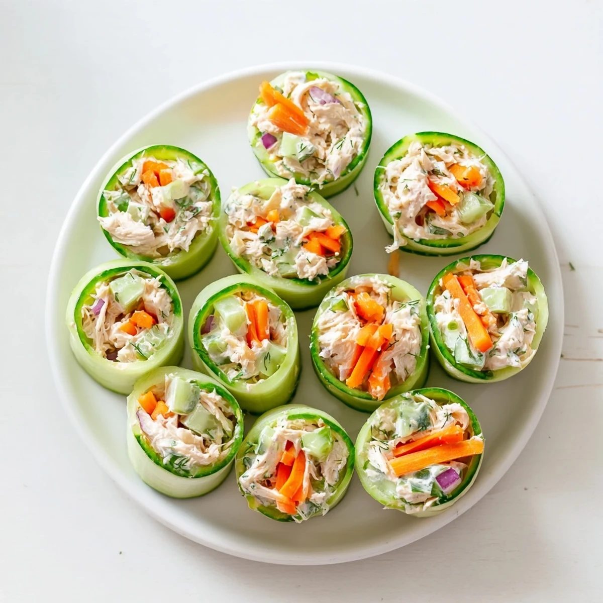 Crisp cucumber roll ups filled with seasoned chicken salad on a white platter