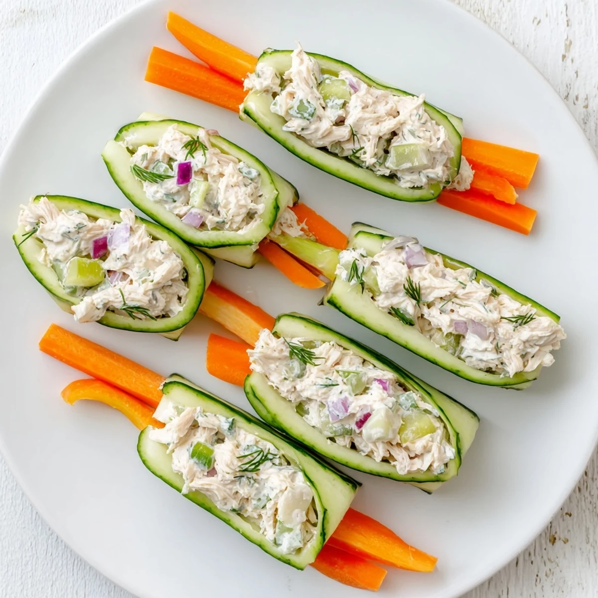 Low carb chicken salad cucumber roll ups garnished with fresh dill and carrots