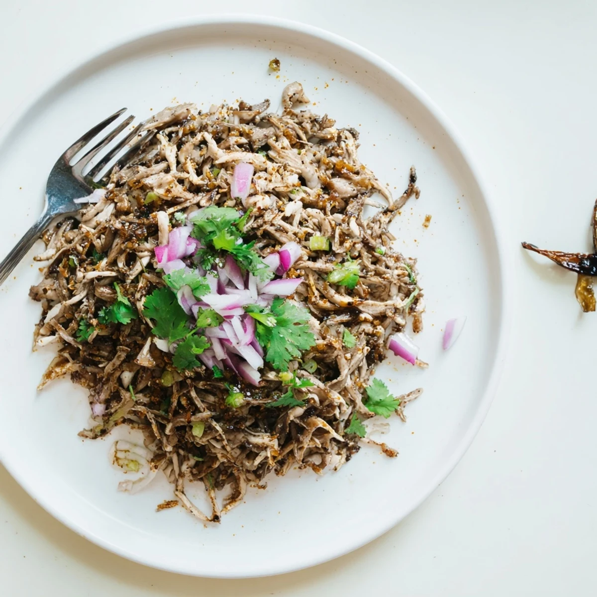 Golden brown vegan carnitas with shredded mushrooms piled in warm corn tortillas