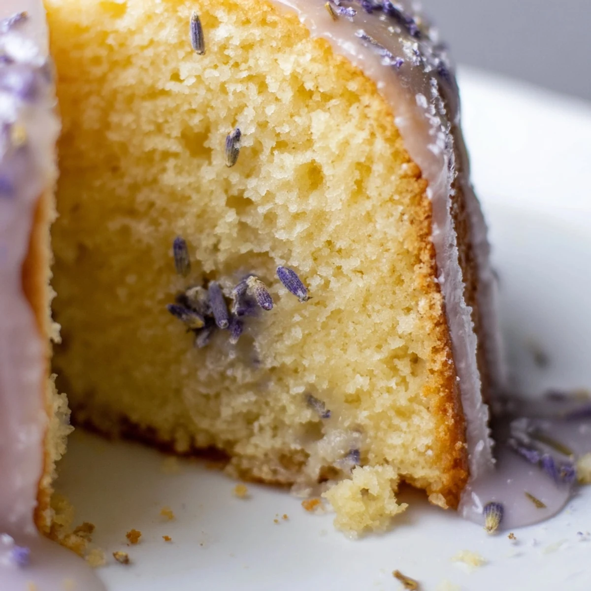 Lavender cake with lemon glaze drizzled over a tender golden crumb studded with purple buds