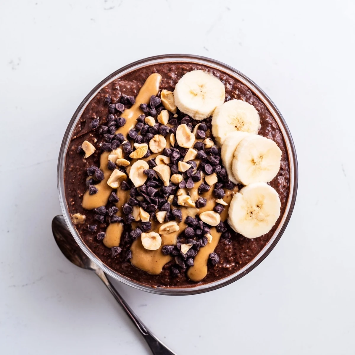 Thick chocolate peanut butter overnight oats served in a mason jar with banana slices