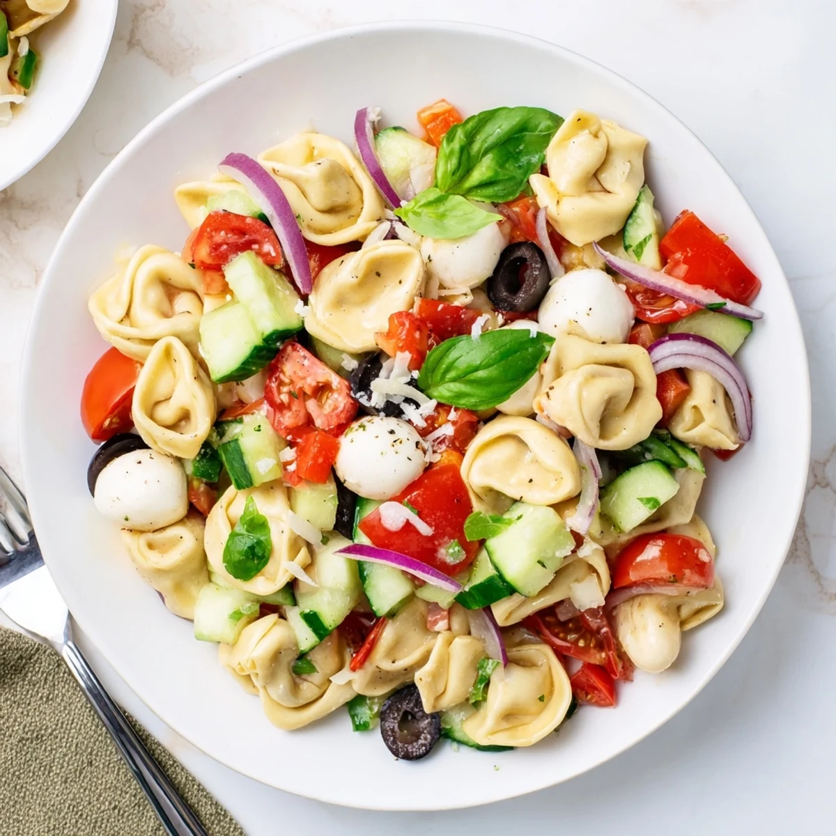 Colorful tortellini salad with cherry tomatoes, cucumber, and zesty Italian dressing in a serving bowl