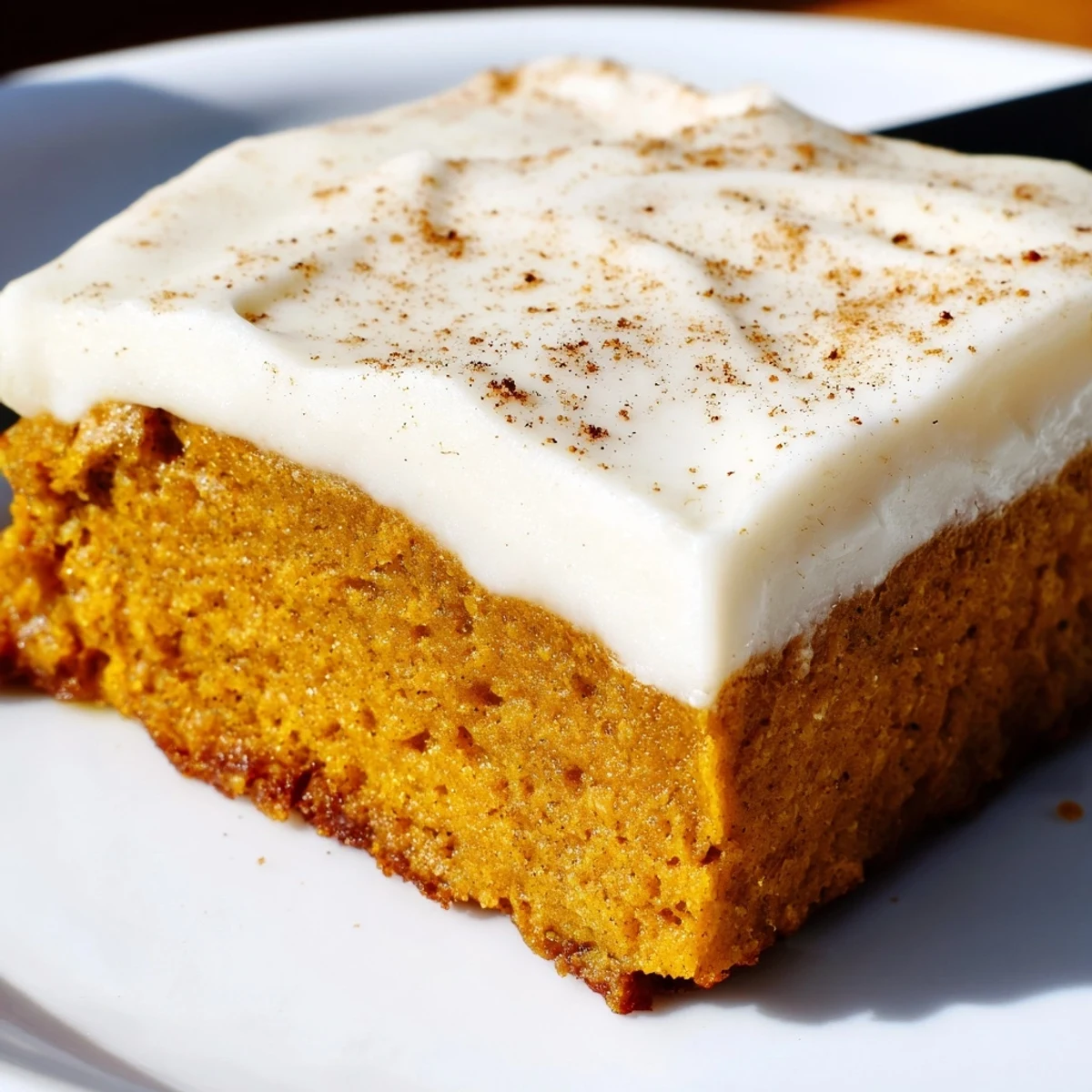Warm spiced pumpkin bars with cream cheese frosting sliced on a rustic cutting board