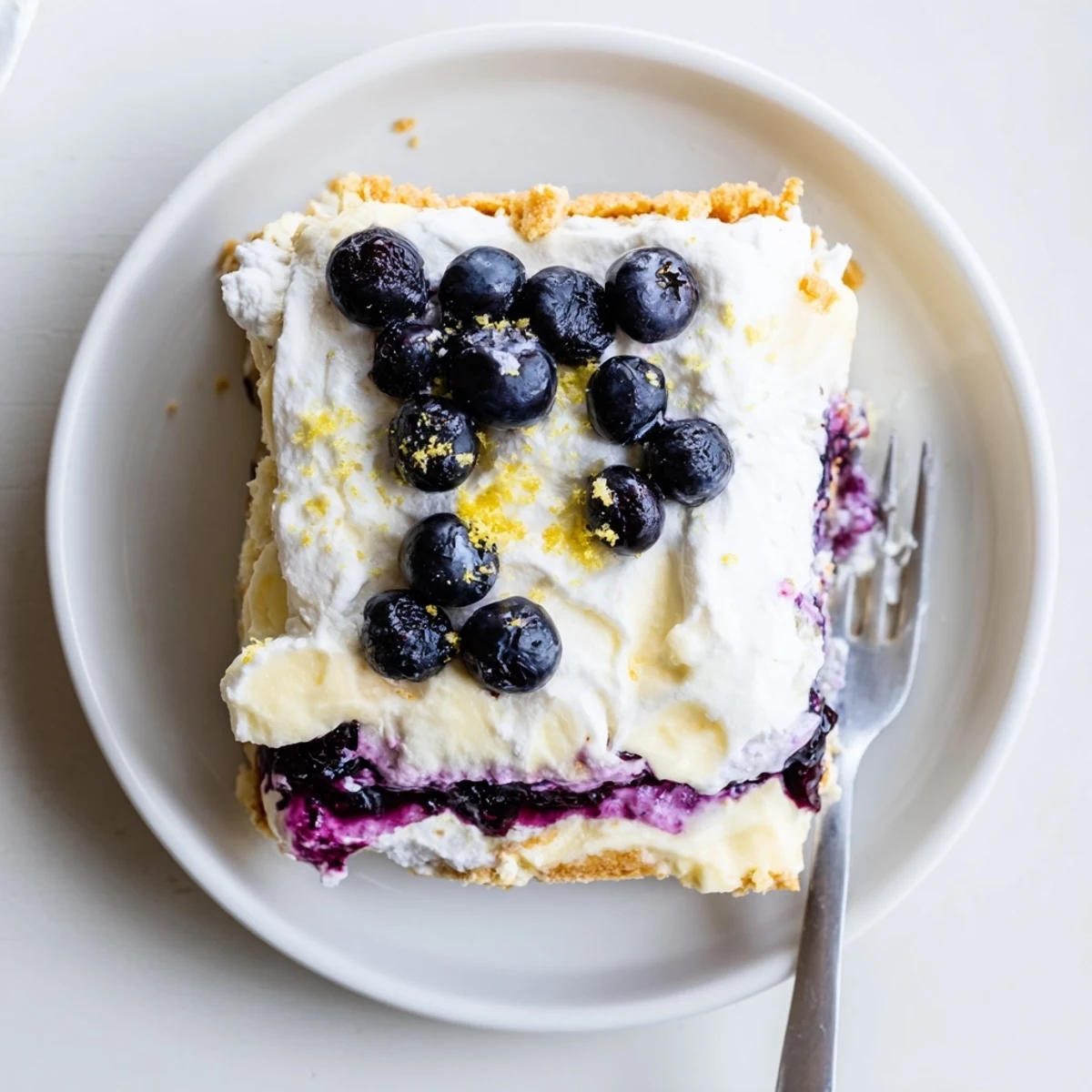 Sliced squares of lemon blueberry lasagna recipe garnished with fresh berries and zest