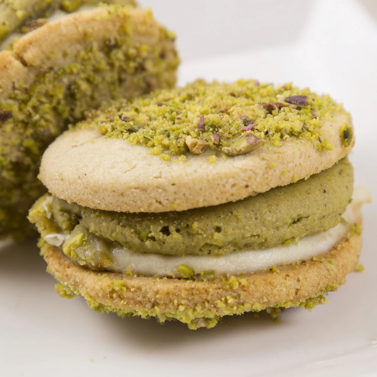 Pistachio Cream Cookies Recipe showcased on a plate, buttery sandwiches, chopped pistachios  