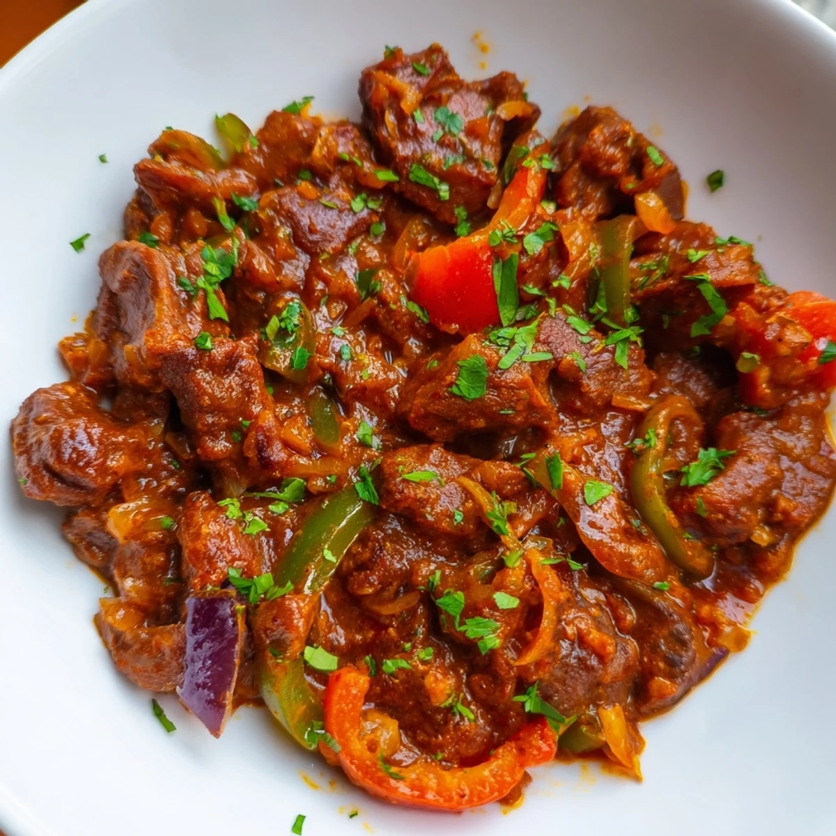 Golden brown Kenyan goat wet fry featuring tender meat in rich spiced tomato gravy with green chilies