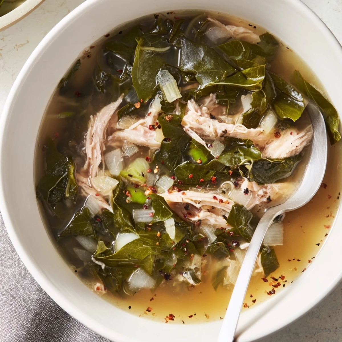 Classic Southern collard greens with shredded meat swimming in a flavorful dark broth, garnished with freshness