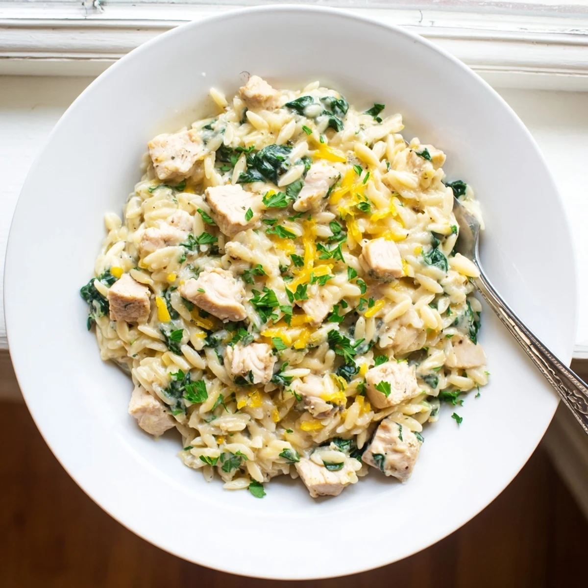 Creamy garlic butter pepper jack chicken orzo simmering in a skillet with melted cheese and wilted spinach