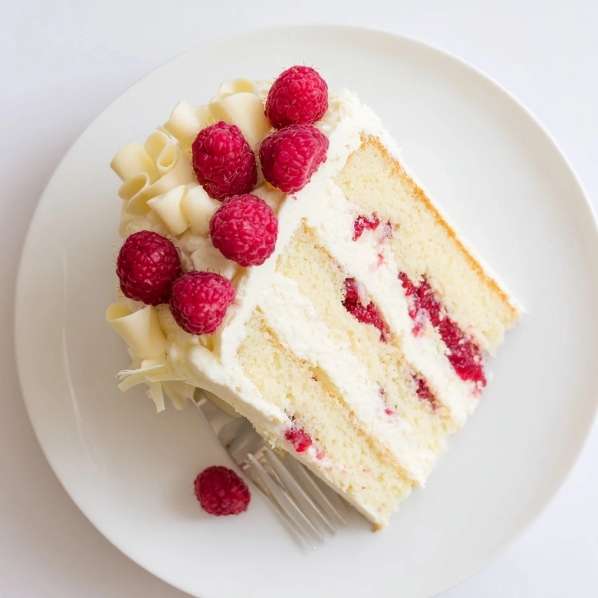 Triple-layer white chocolate raspberry dream cake featuring smooth cream cheese frosting and vibrant red berry filling.